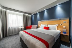a hotel room with a large bed with red pillows at Holiday Inn Express Ramsgate – Minster by IHG in Minster