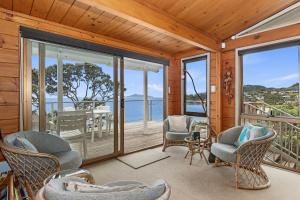 Cette chambre dispose de chaises et d'un balcon avec vue sur l'océan. dans l'établissement Coastal Calm - Langs Beach Holiday Home, à Waipu