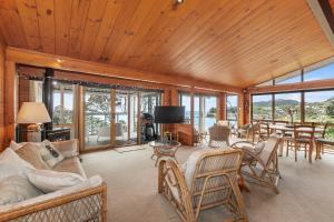 Elle comprend un salon doté de plafonds en bois et de fenêtres en verre. dans l'établissement Coastal Calm - Langs Beach Holiday Home, à Waipu