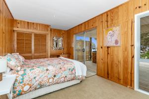 - une chambre avec un lit et une porte coulissante en verre dans l'établissement Coastal Calm - Langs Beach Holiday Home, à Waipu