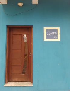 un edificio azul con una puerta de madera y una señal en Pousada Mundo Novo, en Aparecida