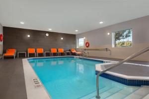 einen Pool in einem Hotelzimmer mit orangefarbenen Stühlen in der Unterkunft Holiday Inn Express Hotel & Suites Barrie, an IHG Hotel in Barrie