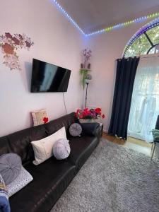 sala de estar con sofá de cuero negro y TV en Luxury Triple Room, en Londres