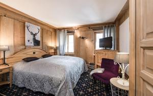 a bedroom with a bed and a chair and a tv at Romantik Hôtel l'Etoile in Charmey