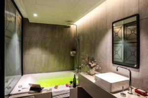 a bathroom with a tub and a sink and a mirror at Mari Hotel Terminal Branch in Jeonju