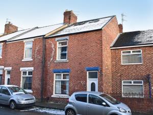 dois carros estacionados em frente a uma casa de tijolos em Seymour House em Bishop Auckland