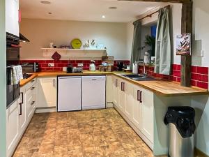 una cocina con armarios blancos y azulejos rojos en Byre Cottage, en Billingshurst