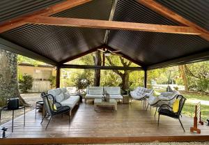 a pavilion with couches and chairs on a wooden deck at Adina Lodge Holiday Apartments in Bright