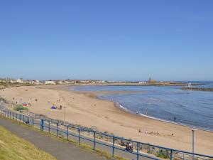 a beach with people on the sand and the water at Rothsay Beach House in Newbiggin-by-the-Sea