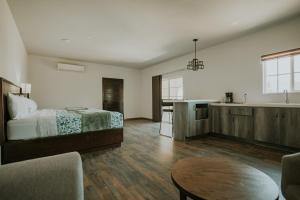 a bedroom with a bed and a kitchen and a table at Hacienda Los Olivos, Valle de Guadalupe in Rancho Grande