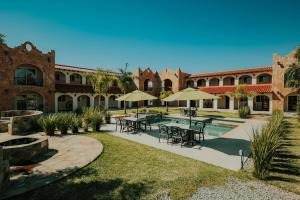 un patio con mesas, sombrillas y una piscina en Hacienda Los Olivos, Valle de Guadalupe, en Rancho Grande