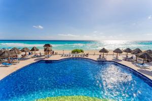 uma piscina na praia com guarda-sóis e cadeiras em Amazing Caribbean Ocean view at Villas Marlin in Cancun em Cancún