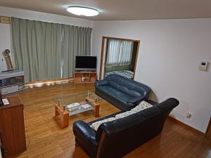 salon ze skórzaną kanapą i szklanym stołem w obiekcie Anna's House w mieście Sapporo