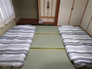 dwa łóżka w pokoju z drzwiami w obiekcie Anna's House w mieście Sapporo