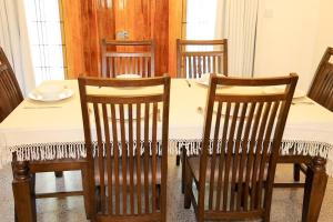 a dining room table with four chairs and a white tablecloth at Lone Star Residence in Jaffna