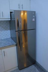 a stainless steel refrigerator in a kitchen with white cabinets at Lone Star Residence in Jaffna