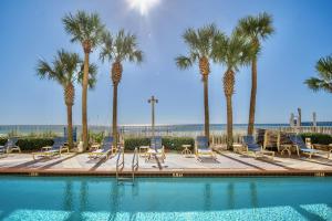 a swimming pool with chairs and palm trees at Beachfront Stunning view 100 ft long swimming pool in Panama City Beach