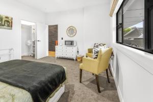 1 dormitorio con 1 cama y 1 silla amarilla en Upper Bow Retreat - Raglan Holiday Apartment en Raglan