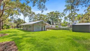 a house in a yard with a large grass field at 60 Yamba Street Hawks Nest in Sydney