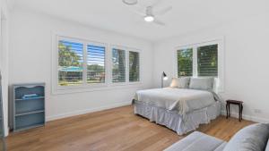 a white bedroom with a bed and two windows at 60 Yamba Street Hawks Nest in Sydney