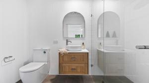 a white bathroom with a toilet and a sink at 60 Yamba Street Hawks Nest in Sydney