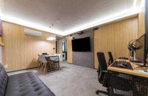 a room with a desk and a table with chairs and a television at Hotel The Araboda in Gwangju