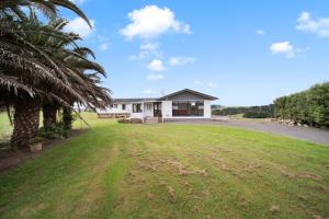 a house with a palm tree in front of a yard at Apartment 4 in Auckland