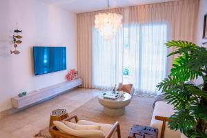 a living room with a tv on the wall and a couch at Fortunity Beach Tower-2 BDR with pool view in San Felipe de Puerto Plata