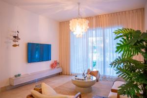 a living room with a tv and a large window at Fortunity Beach Tower-2 BDR with pool view in San Felipe de Puerto Plata