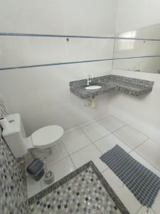 a white bathroom with a toilet and a sink at Casa em iguaba grande in Iguaba Grande