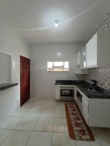 una cocina con armarios blancos y una alfombra roja en el suelo en Casa em iguaba grande, en Iguaba Grande