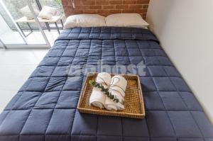 a bed with a blue bedspread and shoes on it at Comfy Loft Bbq Terrace And Balcony in Asuncion