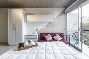 1 dormitorio con 1 cama grande y 1 sofá rojo en Chic Loft With Balcony In Las Mercedes, en Asunción