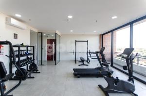 un gimnasio con cintas de correr y elípticas en una habitación con ventanas en Comfortable Los Laureles Loft, en Asunción