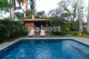 a swimming pool with two chairs and a house at Wonderful Studio In The City, Close To Sh Del Sol in Asuncion