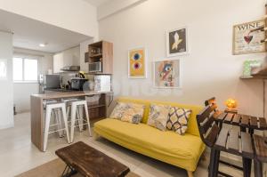 sala de estar con sofá amarillo y cocina en Unbeatable Studio W Pool, Wifi In Villa Morra en Asunción