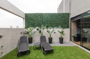 eine Terrasse mit Stühlen und Pflanzen vor einer Wand in der Unterkunft Exclusive And Luxurious Penthouse In Herrera in Asunción
