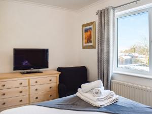 um quarto com uma cama, uma televisão e uma janela em Glebeside Retreat em Satley