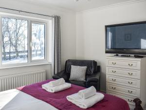 a bedroom with a bed with a chair and a television at Glebeside Retreat in Satley