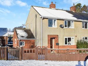 a house with a wooden fence in the snow at Glebeside Retreat in Satley