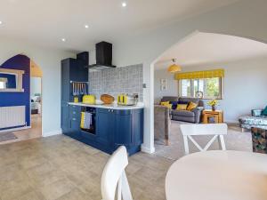 a kitchen with blue cabinets and a living room at Great Tree House in Llangranog