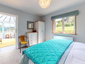 a bedroom with a bed and a chair and windows at Great Tree House in Llangranog