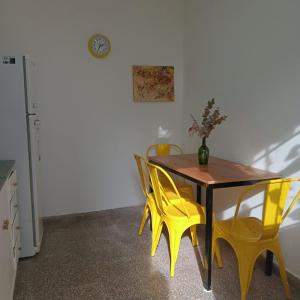 ein Esszimmer mit einem Tisch und gelben Stühlen in der Unterkunft Una casita en la loma in La Plata