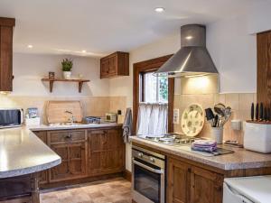 una cucina con armadi in legno e piano cottura. di Quince Cottage a Clifton