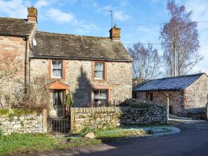 an old stone house with a stone fence in front at Quince Cottage in Clifton