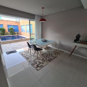 a dining room with a table and chairs and a pool at Casa com piscina a 800 metros da praia de Buraquinho in Lauro de Freitas