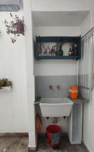 ein Badezimmer mit einem weißen Waschbecken und einem blauen Regal in der Unterkunft Una casita en la loma in La Plata