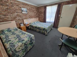 Habitación de hotel con 2 camas y mesa en Dragon Phoenix Resort, en Moree