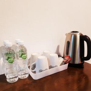 a coffee pot and water bottles on a table at CassaKaseh Guest House in Pantai Cenang
