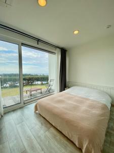 a bedroom with a large bed and a large window at La Pause Pension in Seogwipo